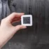 A digital temperature and humidity reading with a condensation-soaked mirror or window in the background.