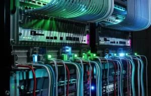 Part of a server rack in close-up, with network cables and glowing lights.