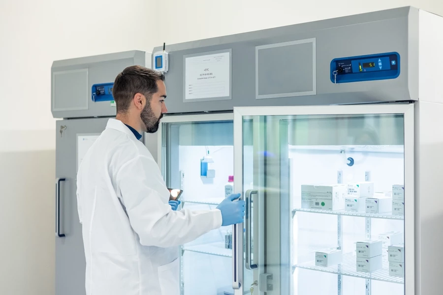 A medical professional reaches into a cold storage fridge for vaccines.